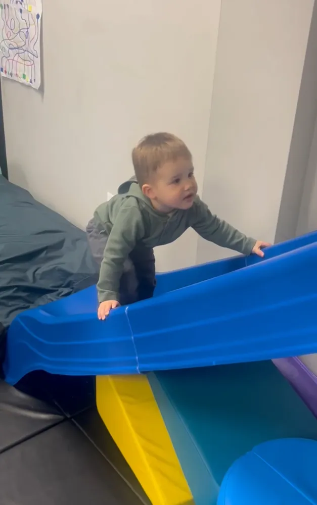 Baby climbing a foam ramp during gross motor play