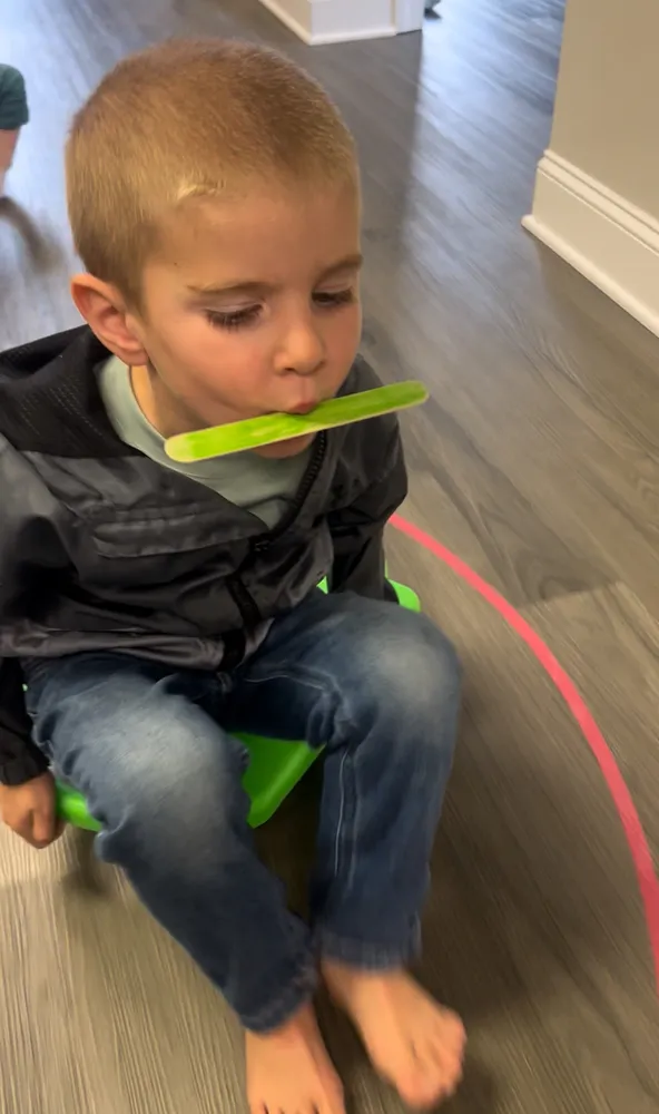 Child using a chewy oral motor tool during therapy