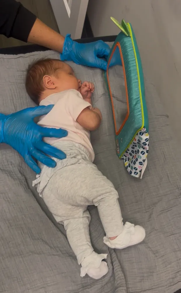 Therapist providing gentle hands-on infant therapy on a mat