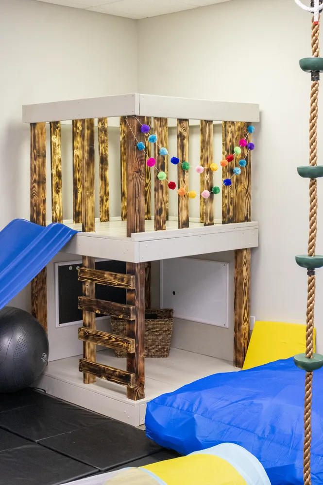 Climbing loft with a rope ladder, therapy ball, and crash mats