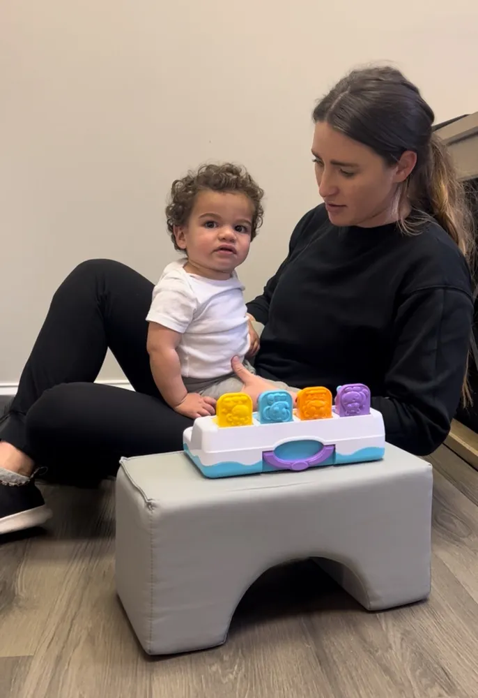 Therapist playing with a toddler and a pop-up toy during a therapy session