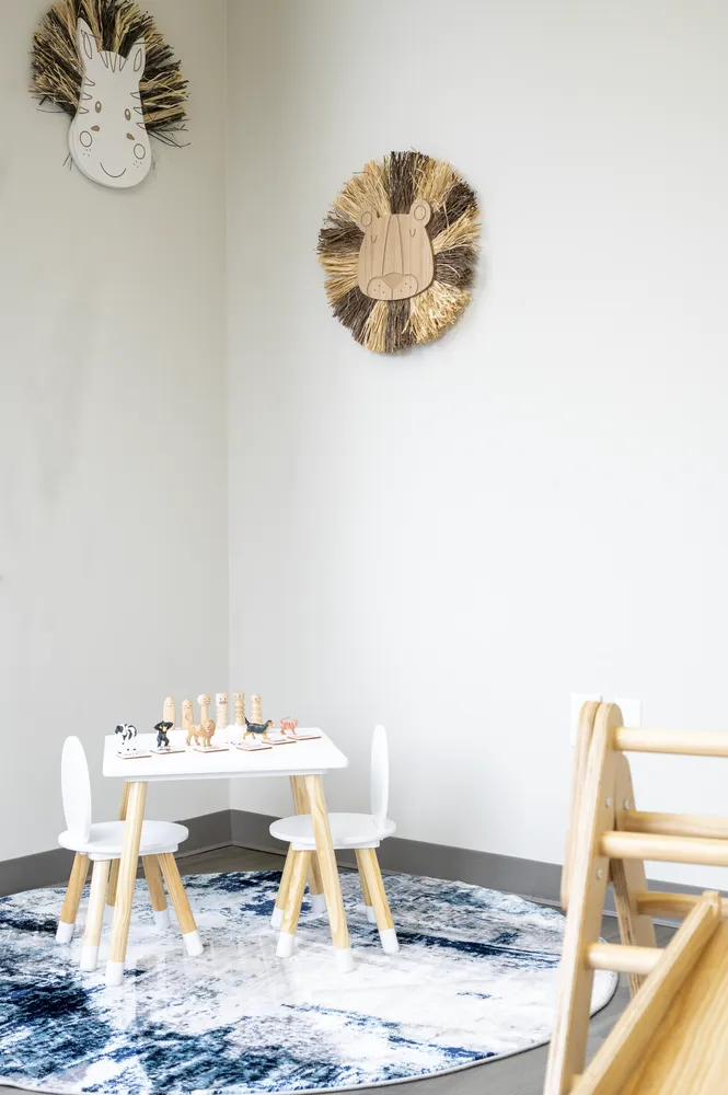Bright therapy room with a child-size table and wooden climbing triangle