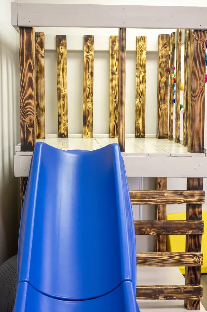Wooden climbing loft with a slide in the pediatric therapy gym